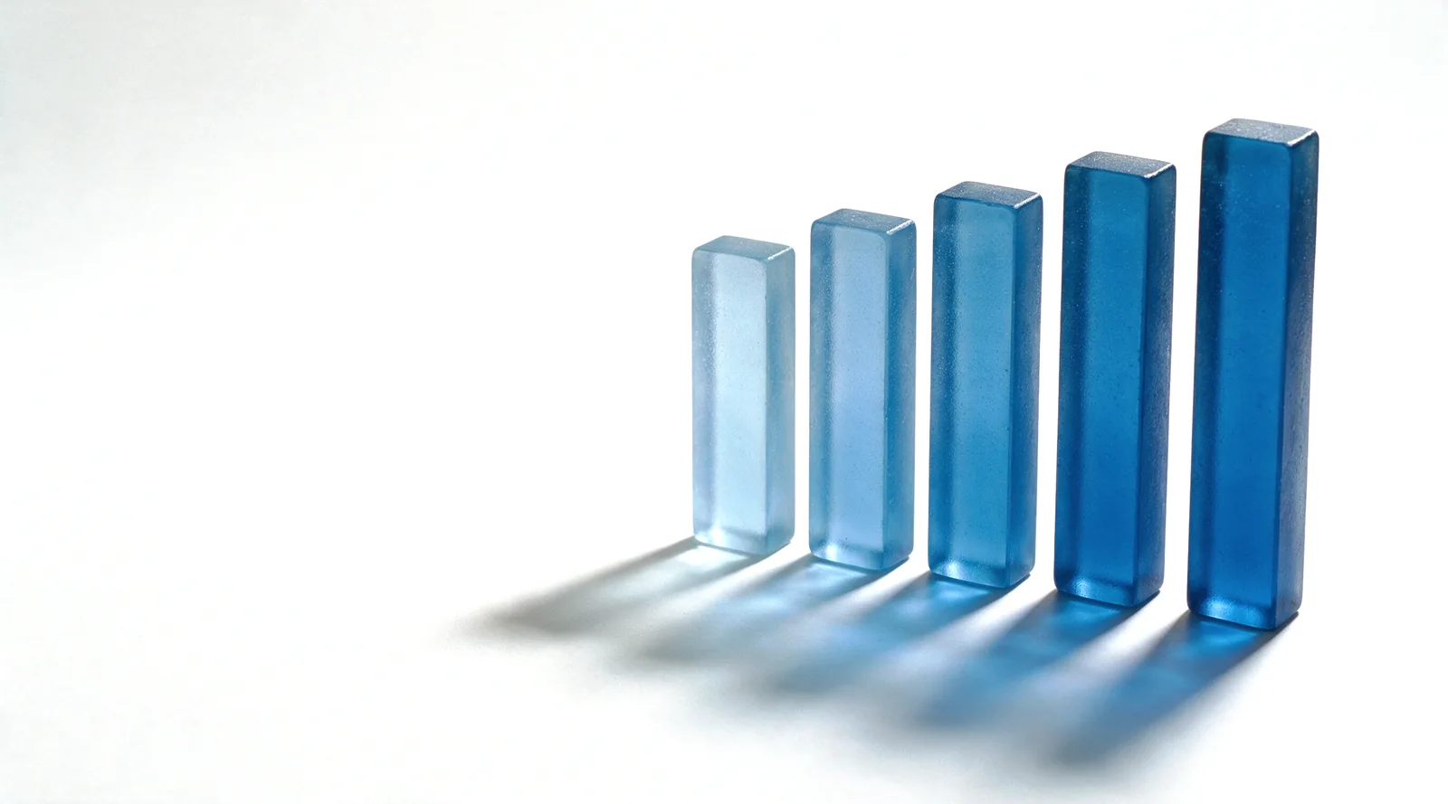 A stepped stack of frosted blue glass bars of rising height on a white studio ground